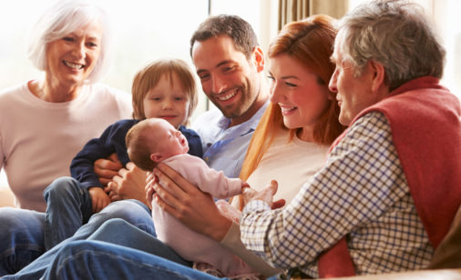 A family sitting on a couch looking at baby