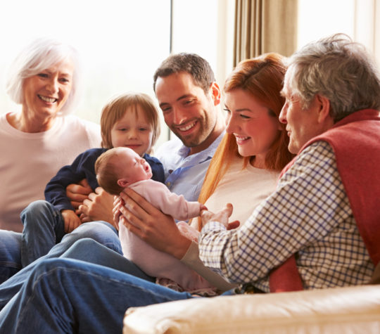 A family sitting on a couch looking at baby