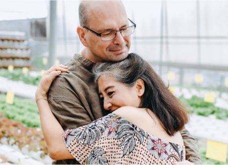 A man and woman hugging in a greenhouse