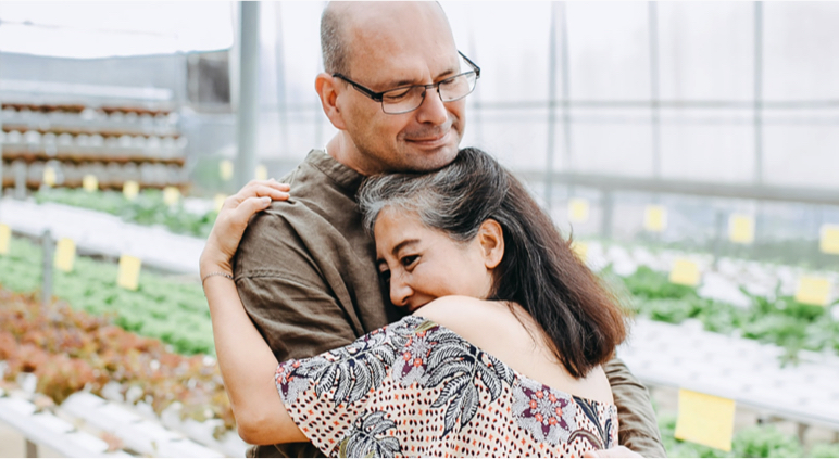 A man and woman hugging in a greenhouse