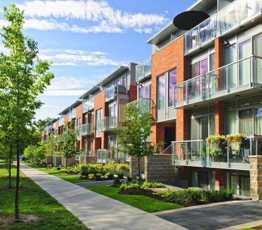 Vue de face de maisons en rangée depuis le trottoir