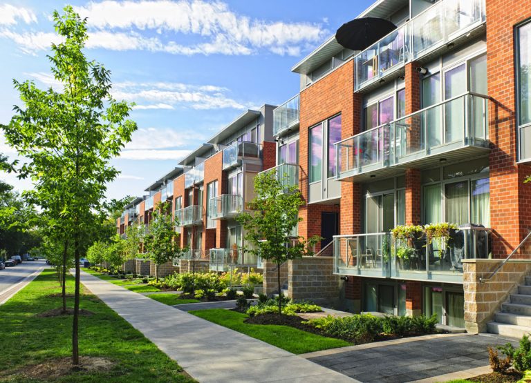 Vue de face de maisons en rangée depuis le trottoir