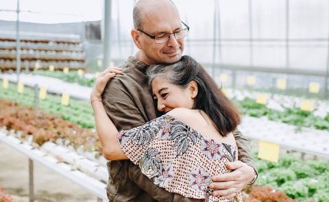 A man and woman hugging in a greenhouse