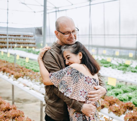 A man and woman hugging in a greenhouse