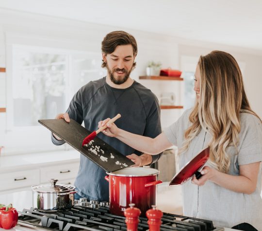 A man and woman cooking on a stovetop