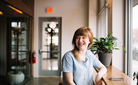 A smiling woman leaning on a wooden ledge