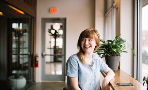 A smiling woman leaning on a wooden ledge