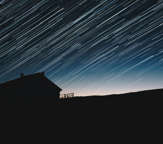 A silhouette of a home in a dark sky