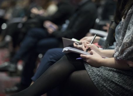 People writing down notes at a conference