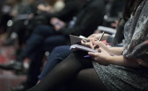 People writing down notes at a conference