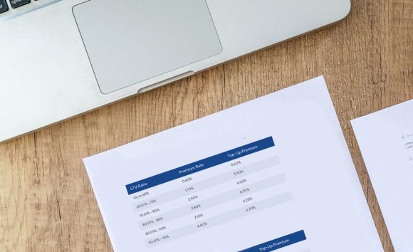 A laptop touchpad and piece of paper showing the Premium Rate Chart