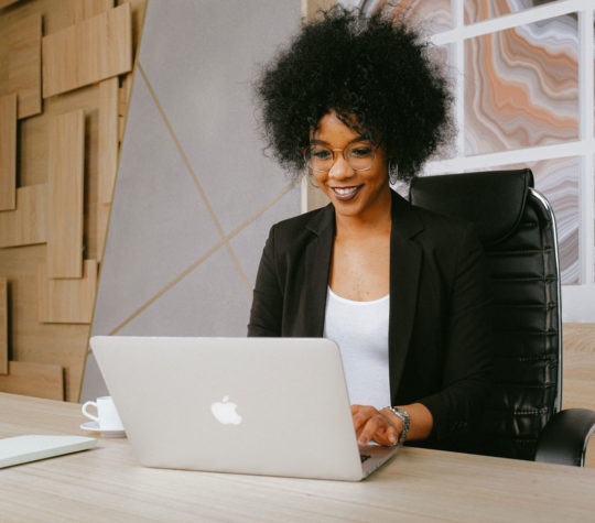 A woman sitting at a table and typing on a laptop