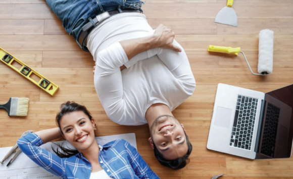 Top-down view of a young man and woman lying on their floor surrounded by tools