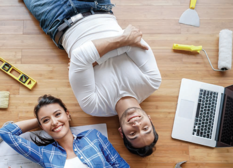 Top-down view of a young man and woman lying on their floor surrounded by tools
