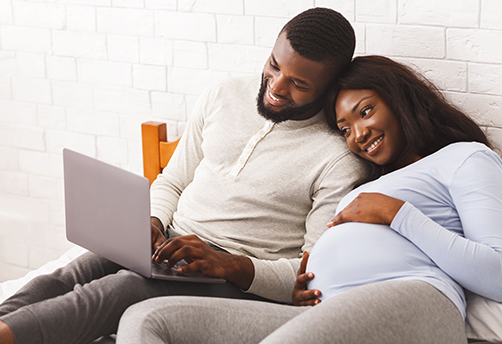 Young couple with pregnant woman looking at laptop
