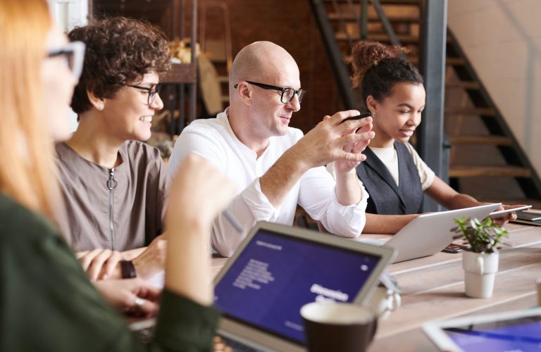 Four people sitting at a table and interacting during a meeting